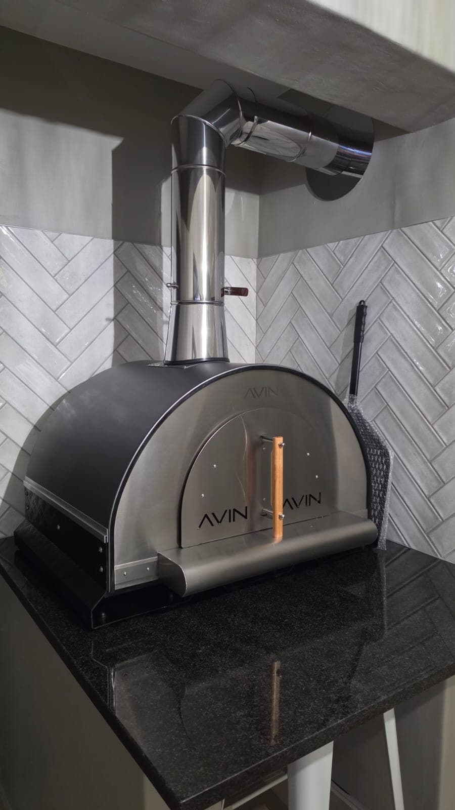 A matt black AVIN with a copper handle against herringbone tiles