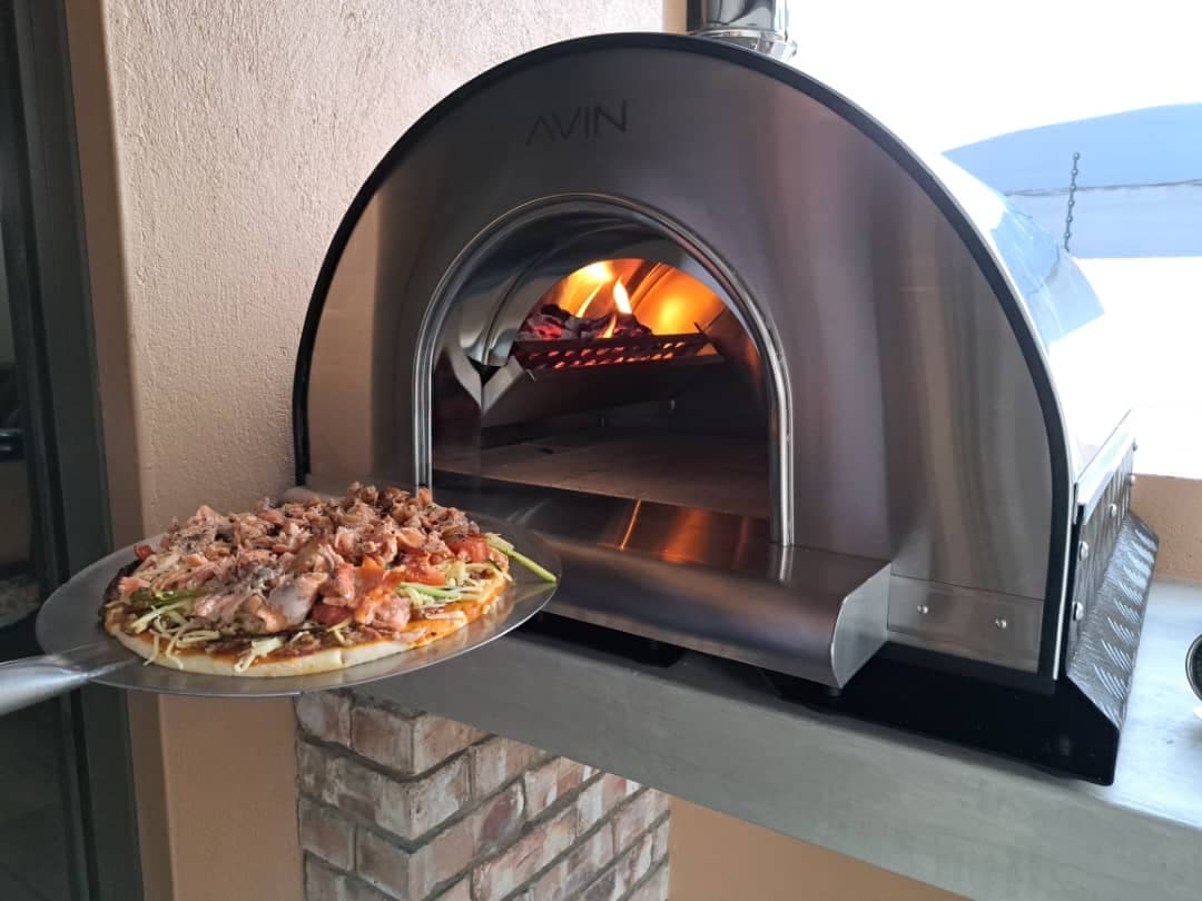 A pizza on a peel going into a fired AVIN